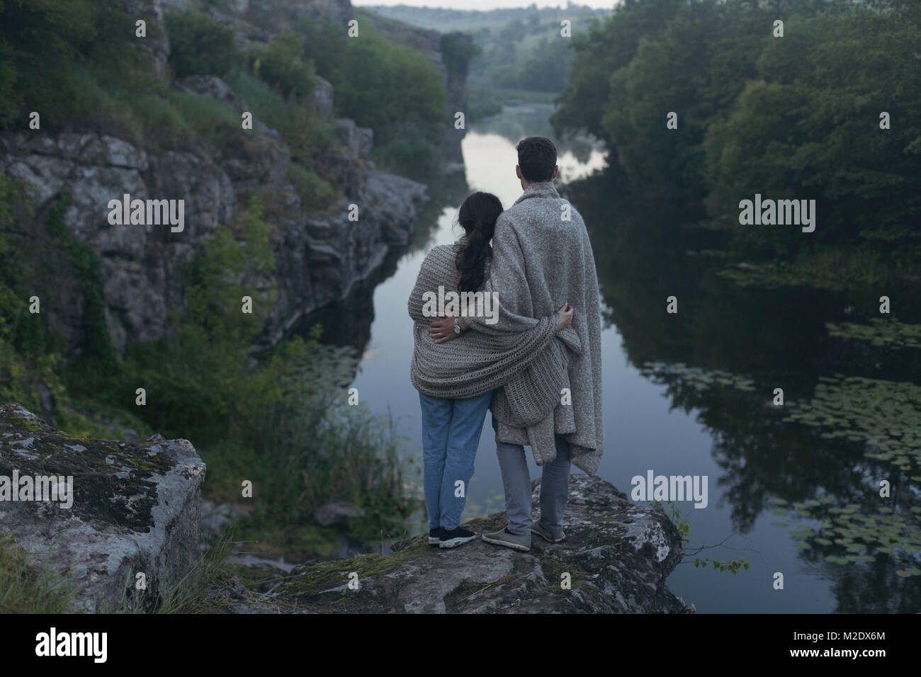 Kaukasische Paar in der Decke eingewickelt steht auf Rock bewundern Fluss Stockfoto
