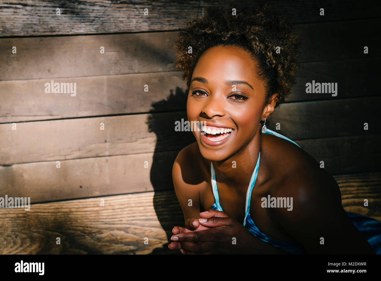 Portrait von lächelnden gemischten Rasse Frau in der Nähe von Holz- wand Lachen Stockfoto