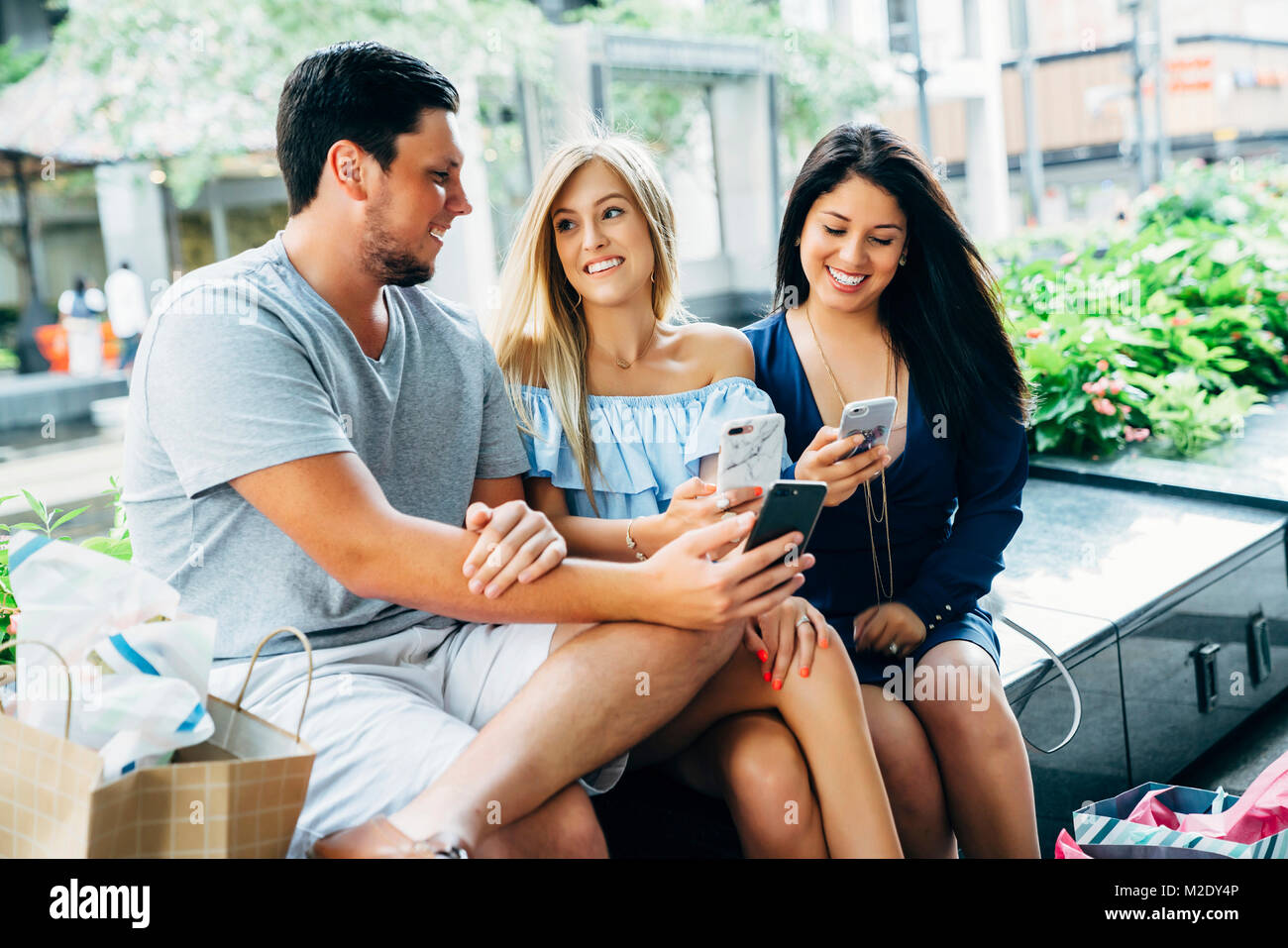 Freunde sitzt auf der Bank von Sms auf Handys Stockfoto