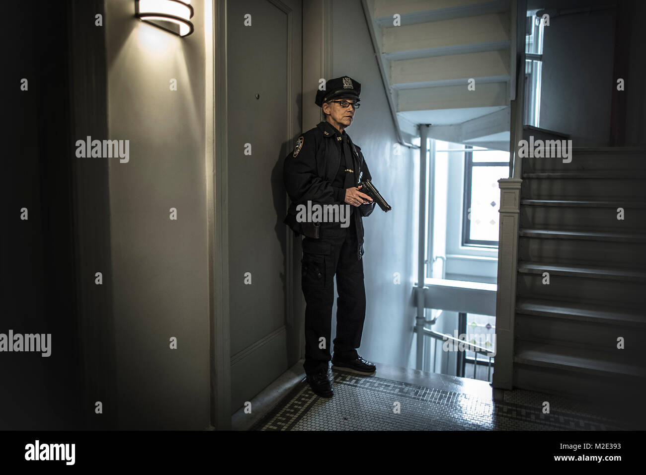 Ältere kaukasischen Polizistin holding Gun in der Wohnung eine Treppe Stockfoto
