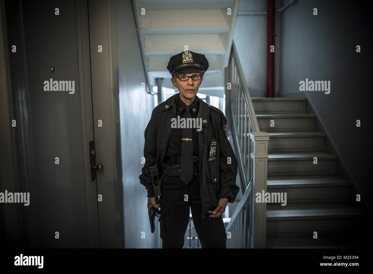 Portrait von älteren Kaukasischen Polizistin holding Gun in der Wohnung eine Treppe Stockfoto