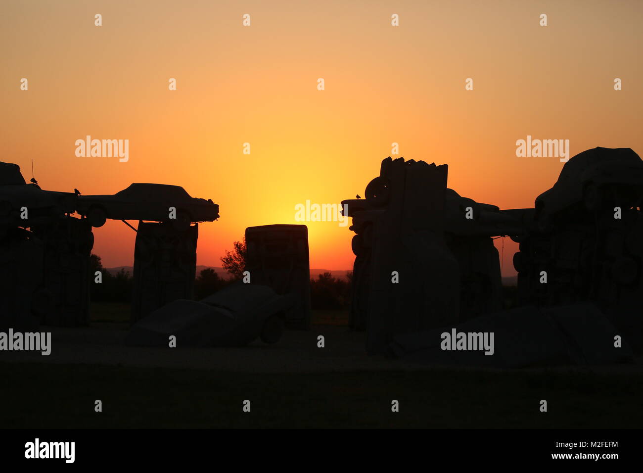 Alliance, Nebraska, USA. 20 Aug, 2017. Die Sonne geht hinter Carhenge, ein Nachbau von Stonehenge. Die totale Sonnenfinsternis über die gesamten Vereinigten Staaten von West nach Ost. Die Stadt der Allianz, NB erwartet 10.000 Besucher das Zentrum der Totalität direkt durch die Stadt. Totalität könnte für 20 Meilen auf beiden Seiten der Mittellinie gesehen werden. Die Stadt insbesondere und Kunst Projekt, Carhenge, über zwei Meilen außerhalb der Stadt wurde eine wichtige touristische Attraktion. Carhenge ist ein Projekt der Besitzer der Farm, die von Stonehenge aufgenommen wurde. Er widmete einen großen Grundstück zu einem Leben Größe Stockfoto