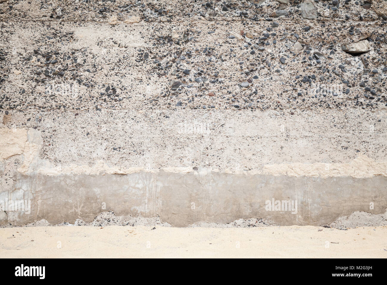 Alte Betonwand mit Steinen und sandigen Boden, leeren Innenraum Hintergrund Foto Textur Stockfoto