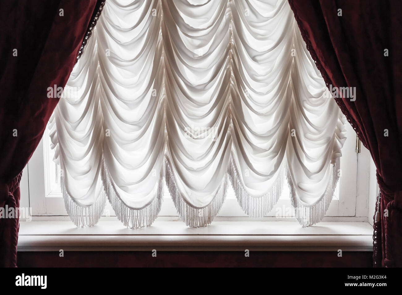 Winkende Tüll und dunklen roten Vorhang Abdeckung weißes Fenster. Hintergrund Foto Textur Stockfoto