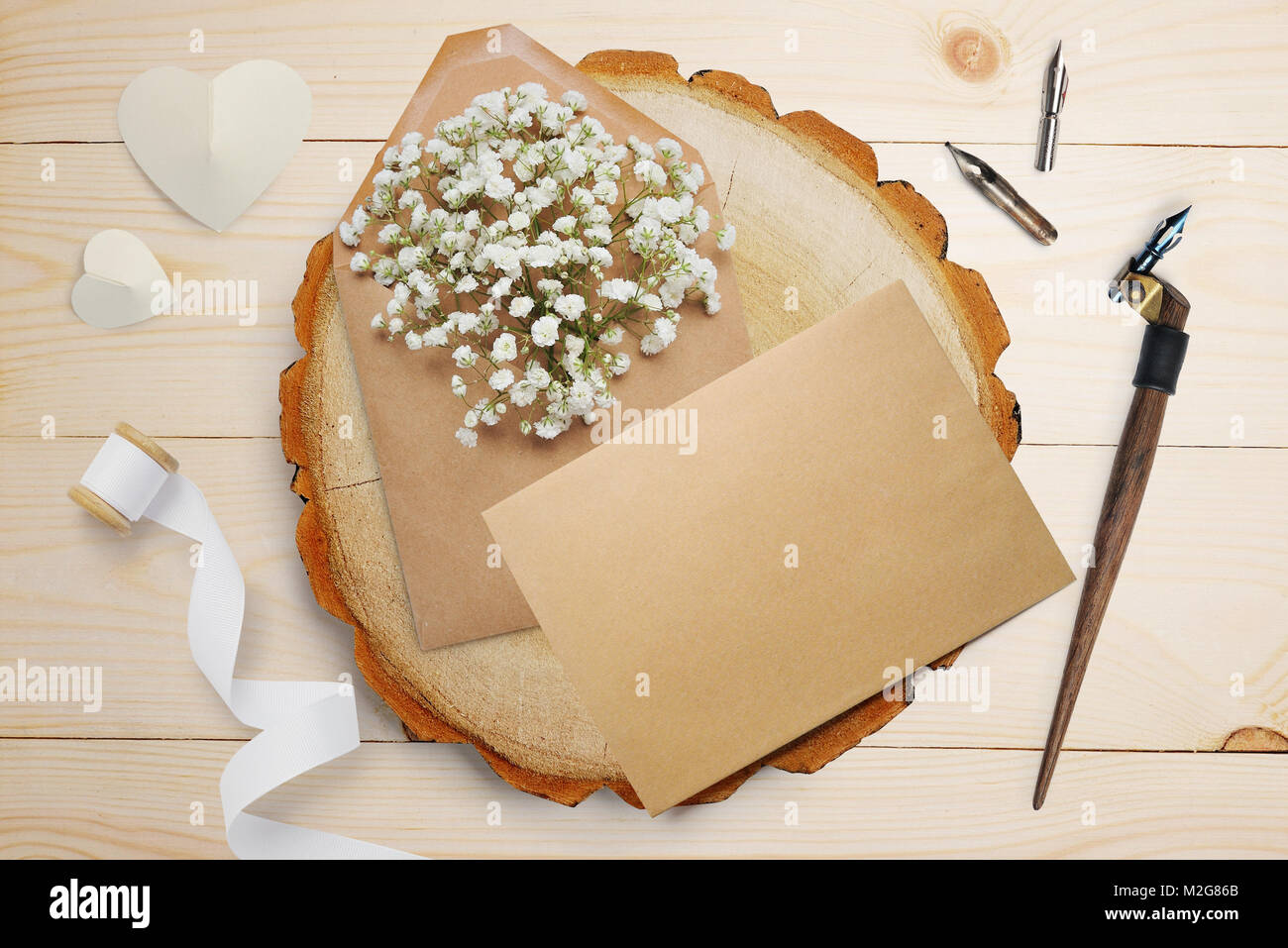 Kalligrafische Feder, liegt in der Nähe eines Holz- Kreis mit weißem Papier Herzen. Grußkarte für Valentines Tag mit Platz für Ihren Text. Flach, Ansicht von oben Foto Mock up Stockfoto