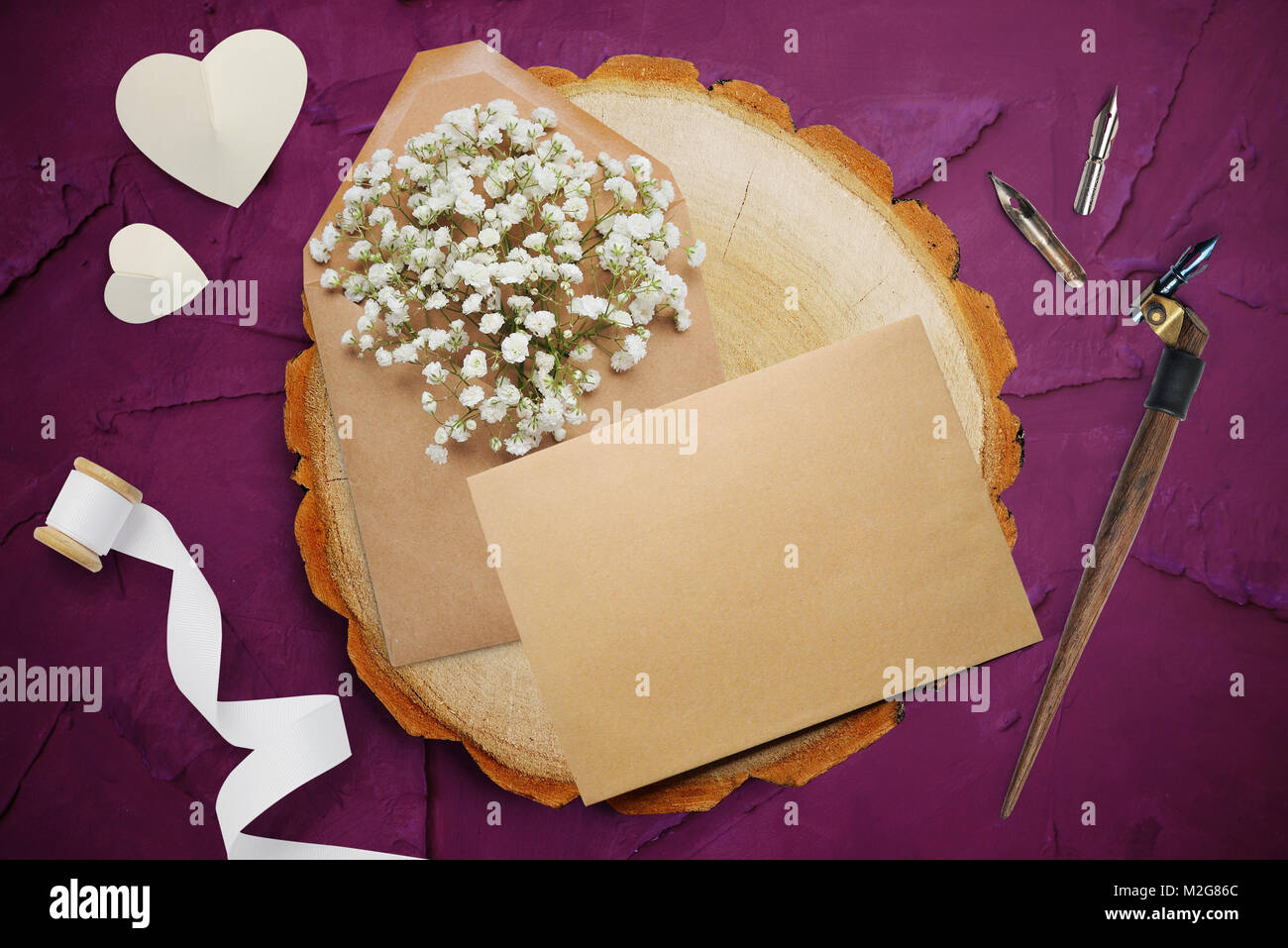 Kalligrafische Feder, liegt in der Nähe eines Holz- Kreis mit weißem Papier Herzen. Grußkarte für Valentines Tag mit Platz für Ihren Text. Flach, Ansicht von oben Foto Mock up Stockfoto