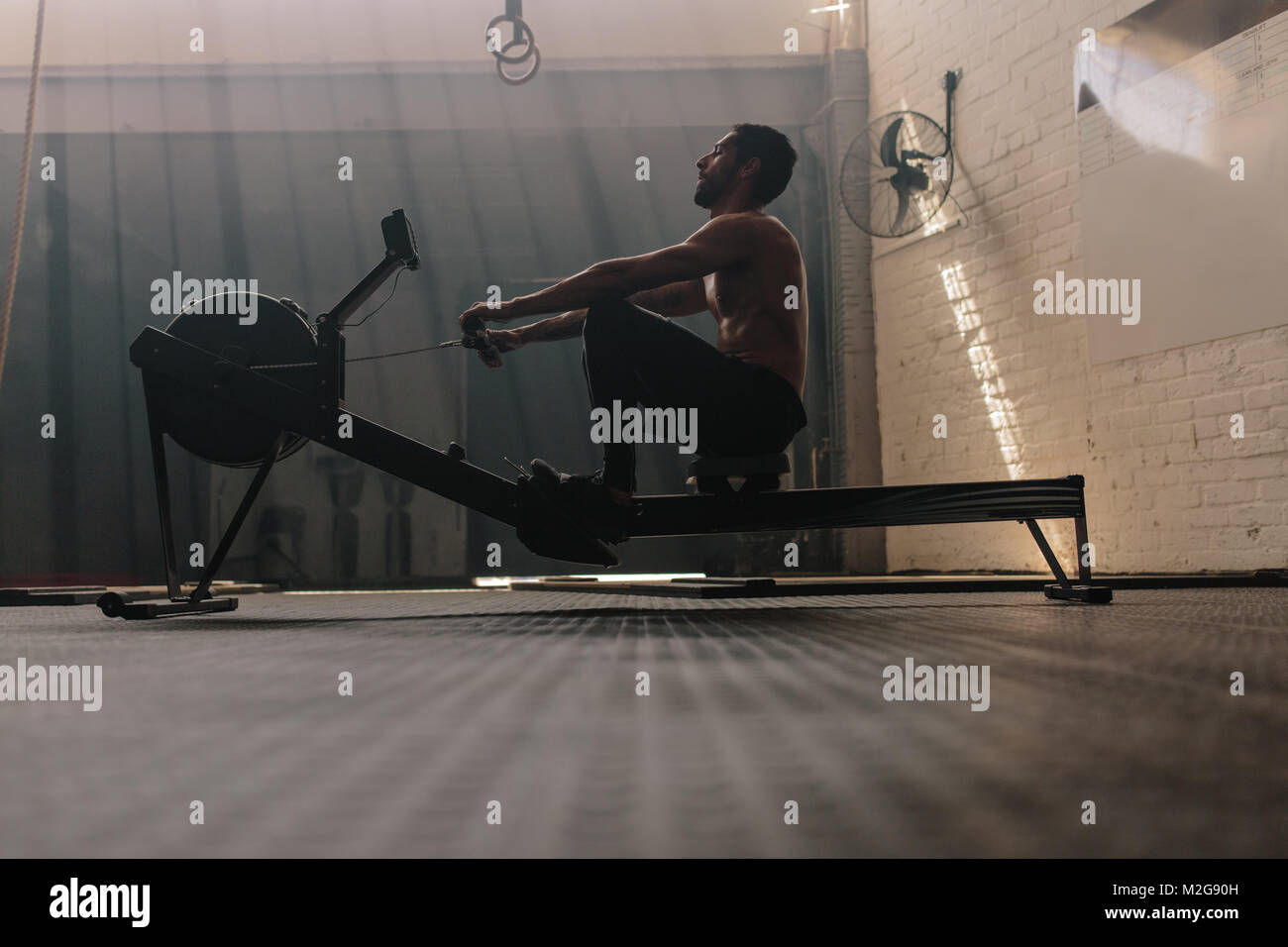 Muskulös mit männlichen Rudergerät in der Turnhalle. Passen Mann tun Workout im Fitness Club. Stockfoto