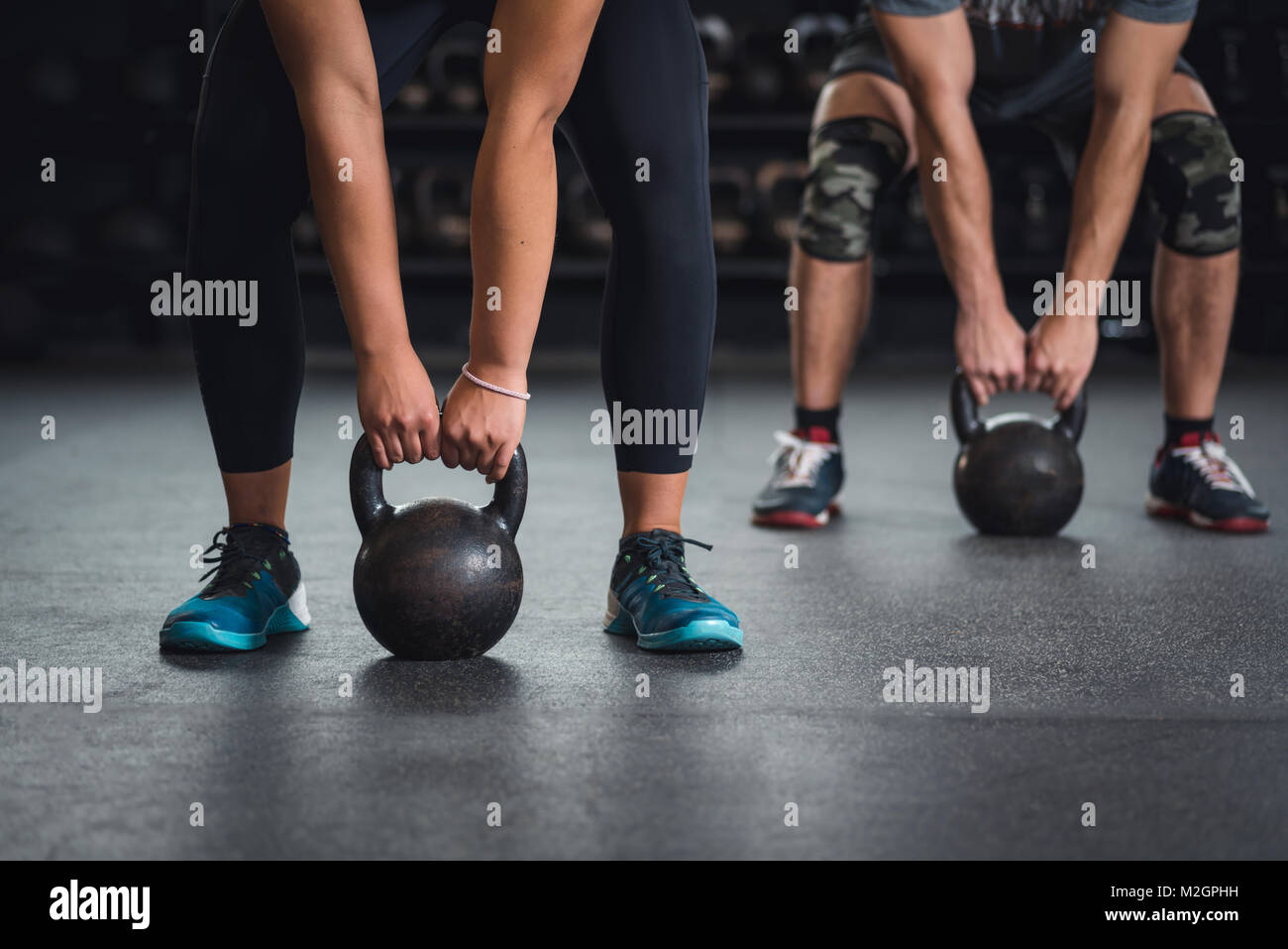 Frauen und Männer in der Turnhalle, gemeinsam in der Gruppe oder Mannschaft anheben Kettlebells. Stockfoto