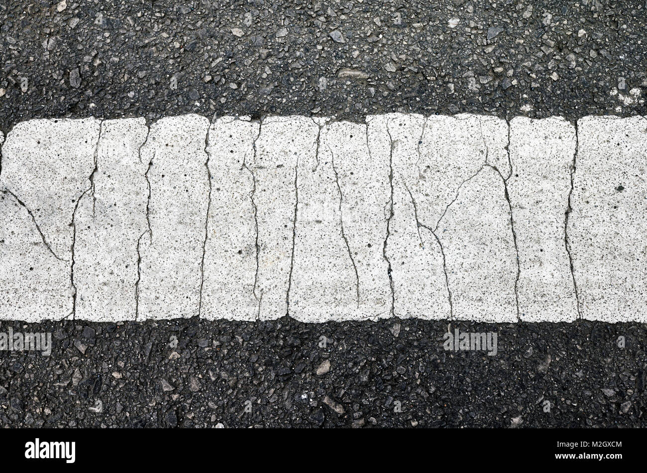 Nahaufnahme Bild über eine asphaltierte Straße mit einem Gesprungenen weiße Fahrbahnmarkierung. Stockfoto