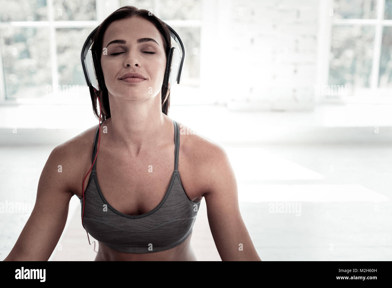 Freudige Dame hören von Musik während der Meditation Stockfoto