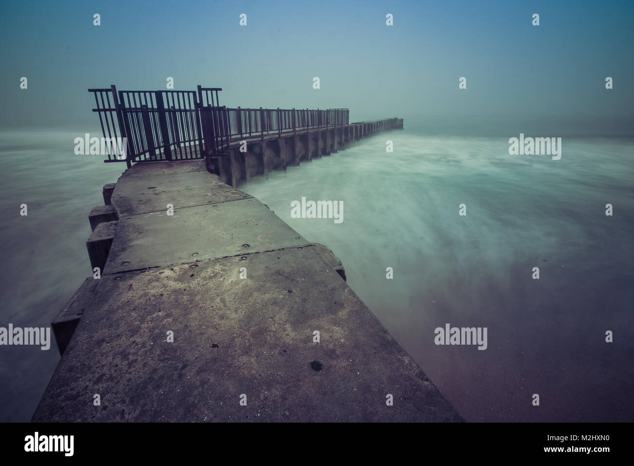 Lange Belichtung Foto von Wellen in McGurk Beach Jetty an einem nebligen Tag in der Dämmerung, Zehen Strand, Playa Del Rey, Kalifornien Stockfoto