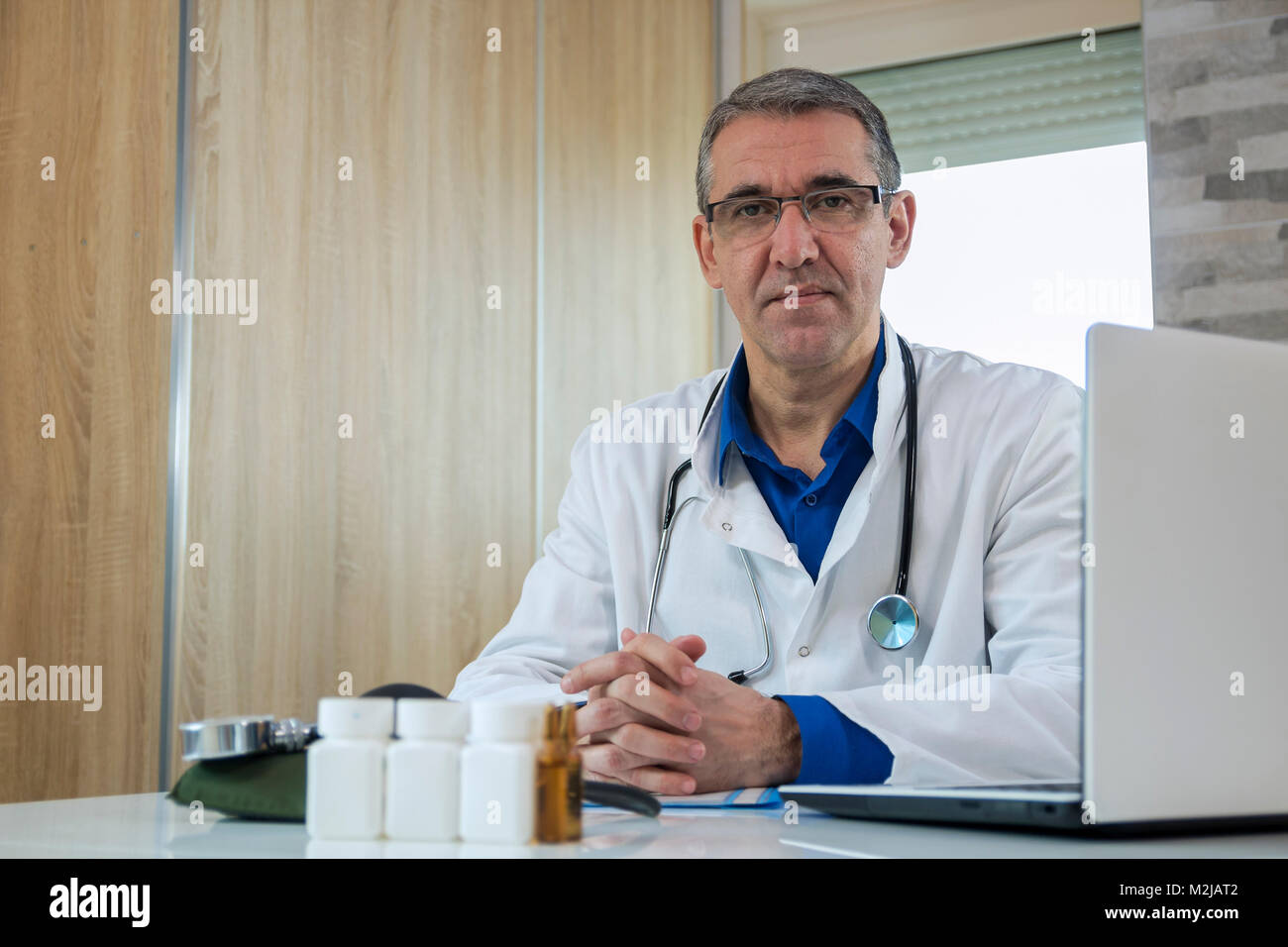 Zuversichtlich Arzt sitzen im Büro und auf Kamera, Gesundheitsversorgung und Prävention. Der Arzt im weißen Kittel mit einem Stethoskop d Stockfoto