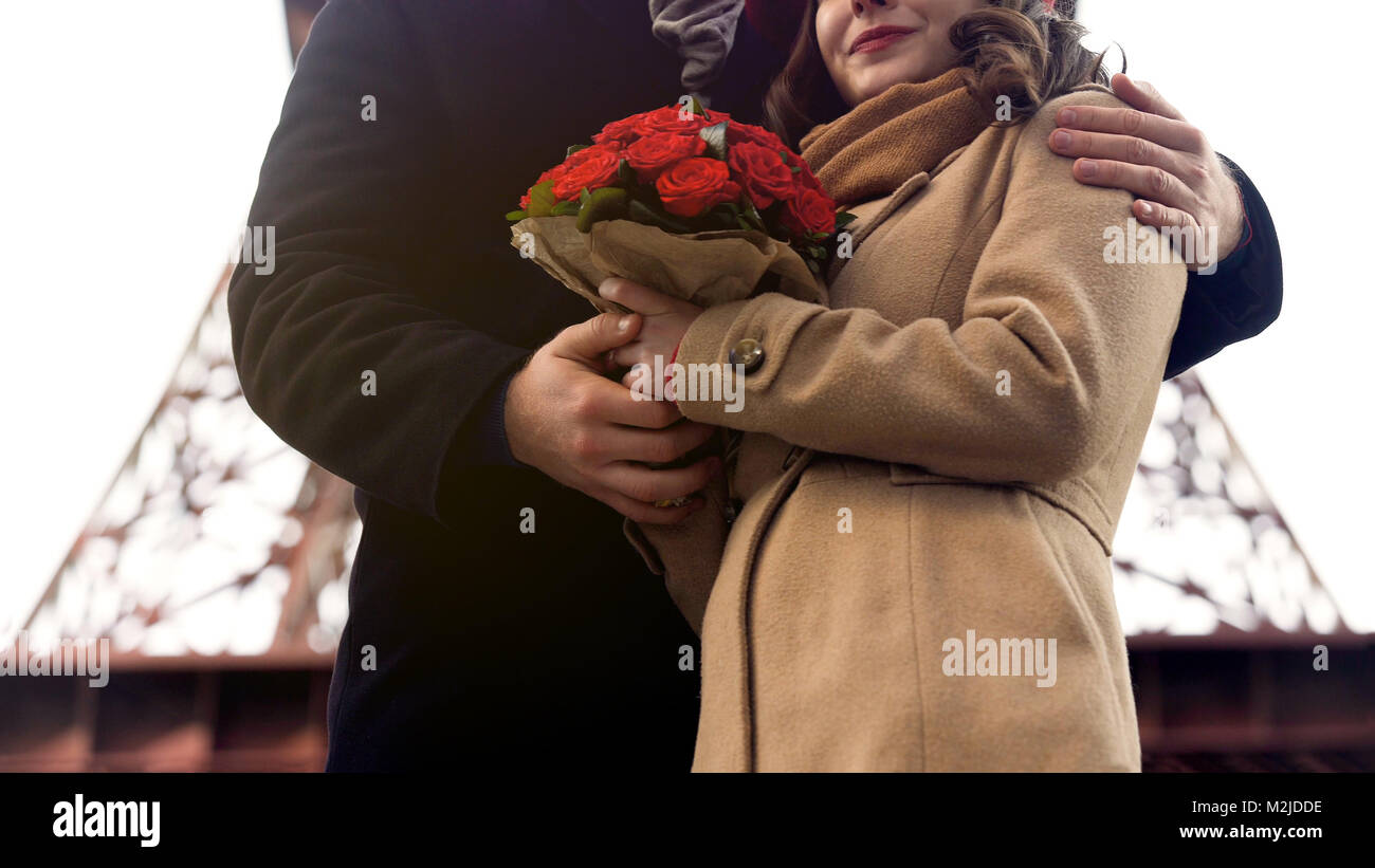 Man sanft Umarmen geliebte Frau mit schönen Blumen in den Händen, Romantik in Paris, Filmmaterial Stockfoto