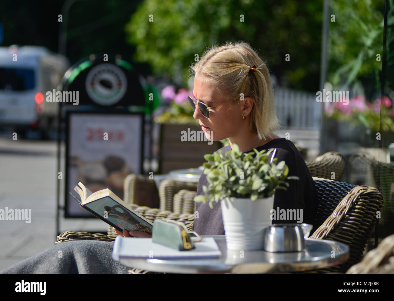 Eine blonde Studentin ein Buch lesen und dabei einen Kaffee am Morgen. Oslo, Norwegen Stockfoto