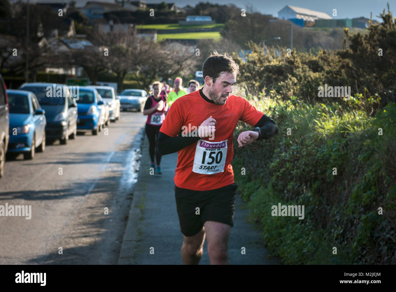 Ein Läufer seine Zeit bei einem Straßenrennen in Newquay Cornwall prüfen. Stockfoto