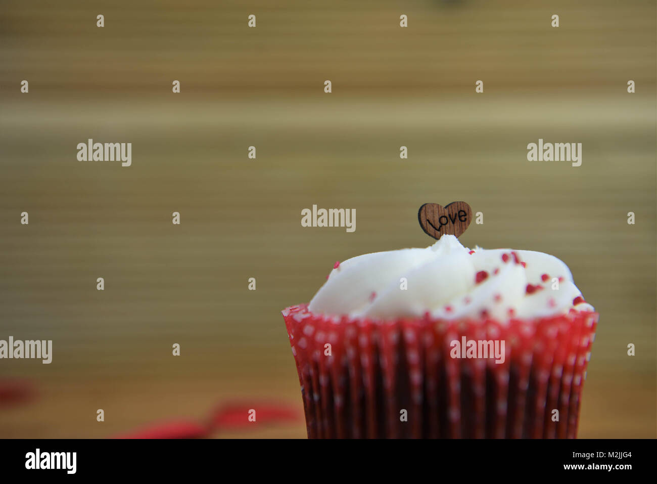 Köstliche Valentines Tag handgefertigte Cupcake mit buttercream und roten besprüht und Holz- Liebe Herz formen und das Wort Liebe Stockfoto