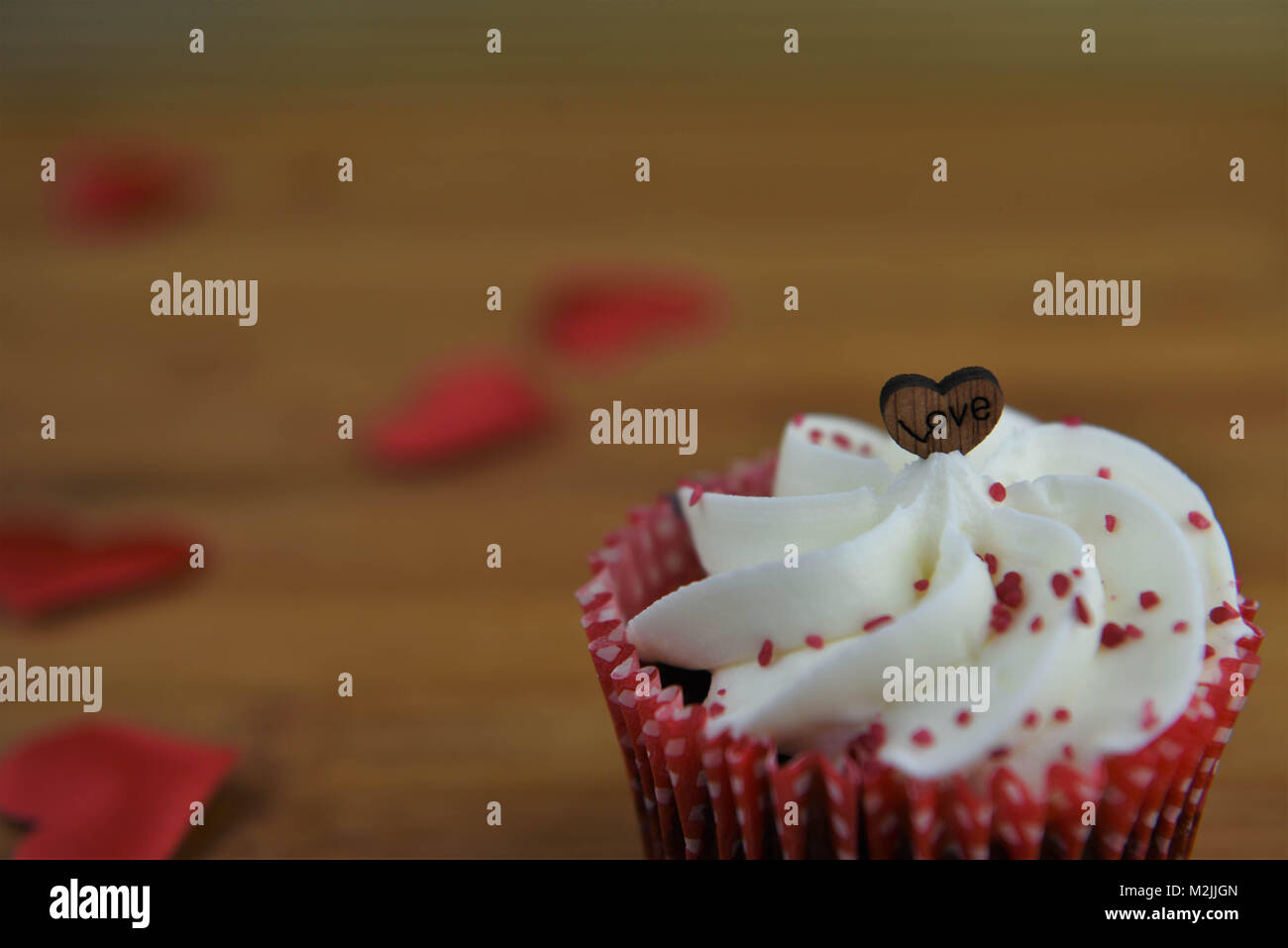 Köstliche Valentines Tag handgefertigte Cupcake mit buttercream und roten besprüht und Holz- Liebe Herz formen und das Wort Liebe Stockfoto