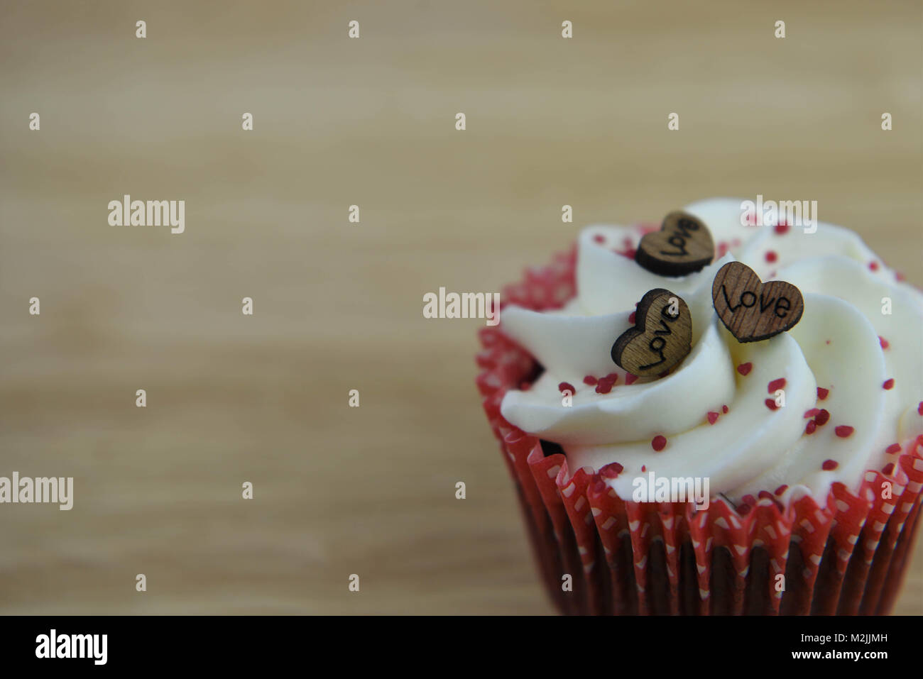 Köstliche Valentines Tag handgefertigte Cupcake mit buttercream und roten besprüht und Holz- Liebe Herz formen und das Wort Liebe Stockfoto