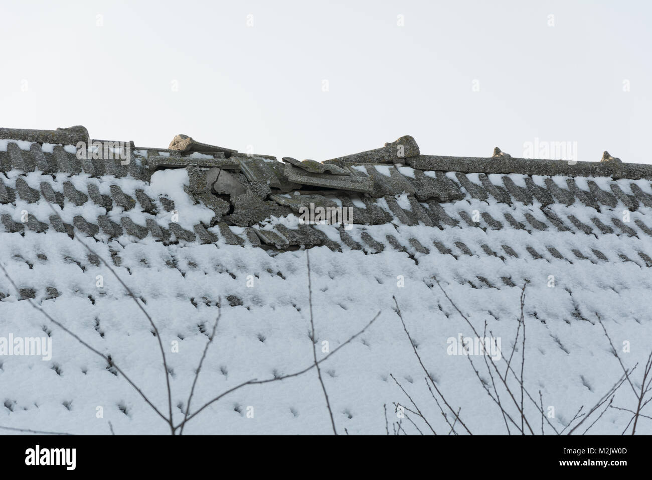 Eine gebrochene Fliesen- Dach mit Schnee bedeckt Stockfoto