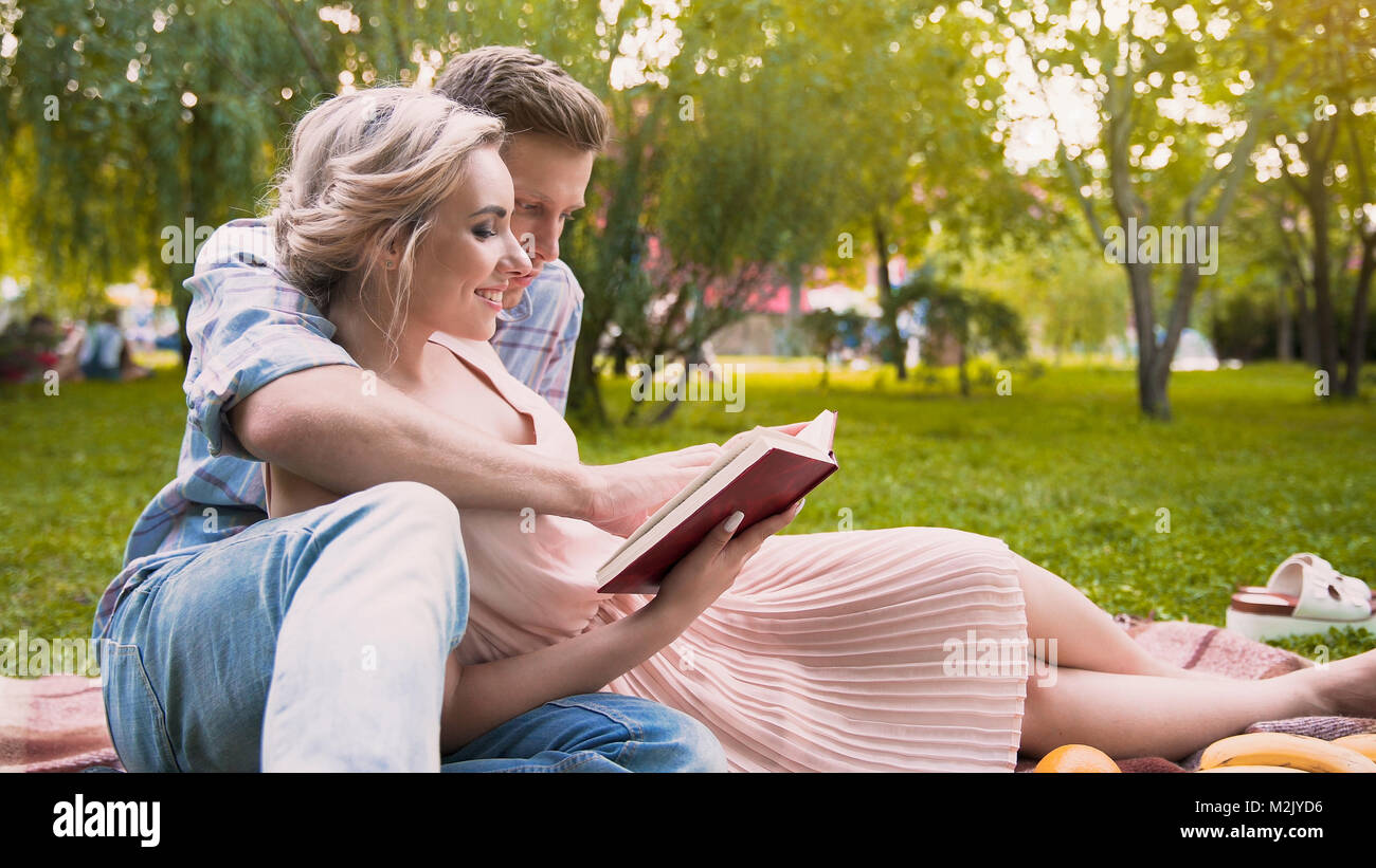 Caring Guy lesen Geschichte zu seiner schönen Frau, sanft Ihre, Datum in Park umarmen Stockfoto