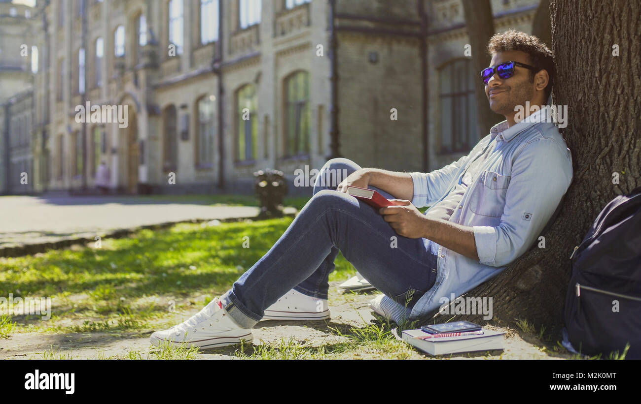 Multirassischen Mann sitzt unter dem Baum mit Sonnenbrille, positive Stimmung, Energie Stockfoto