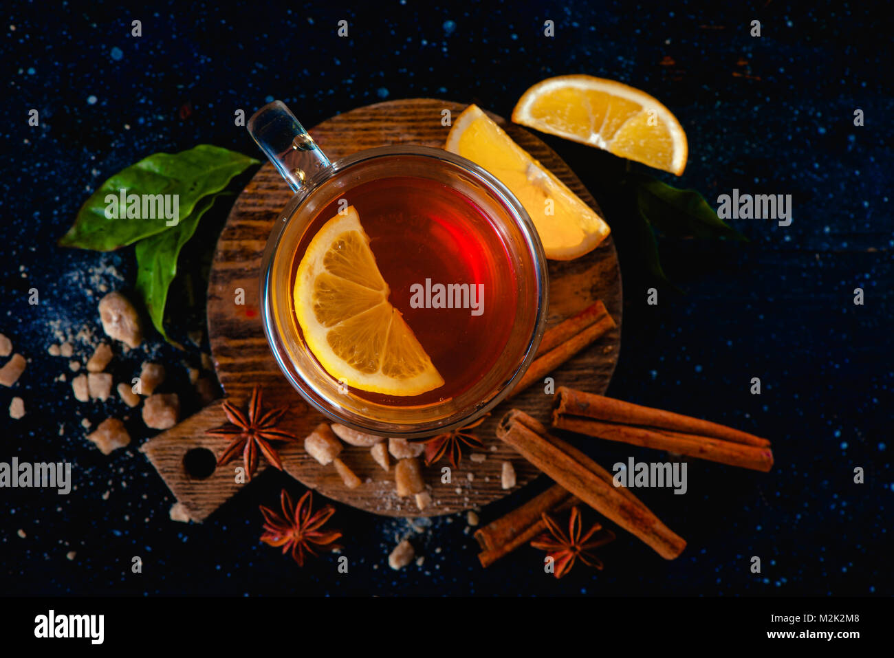 Dunkle Stillleben mit Wasserglas, Zitronenscheiben, Anis Sterne, Zucker, Tee und Zimt auf einem dunklen Hintergrund. Herbst Tee Tasse von oben. Kopieren Sie Platz. Stockfoto