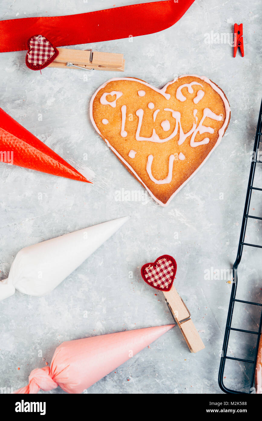 Backen Herzförmige Plätzchen zum Valentinstag, mit farbigen Spritzbeutel, die von Weiß, Rosa und Rot und ein Cookie mit "ich liebe Dich" geleitet. Stockfoto
