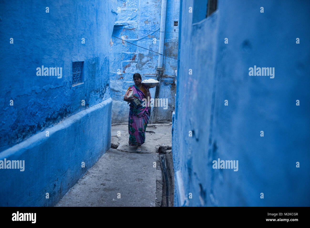 Frau Tragen einer Last in die blaue Stadt Jodhpur, Rajasthan, Indien Stockfoto