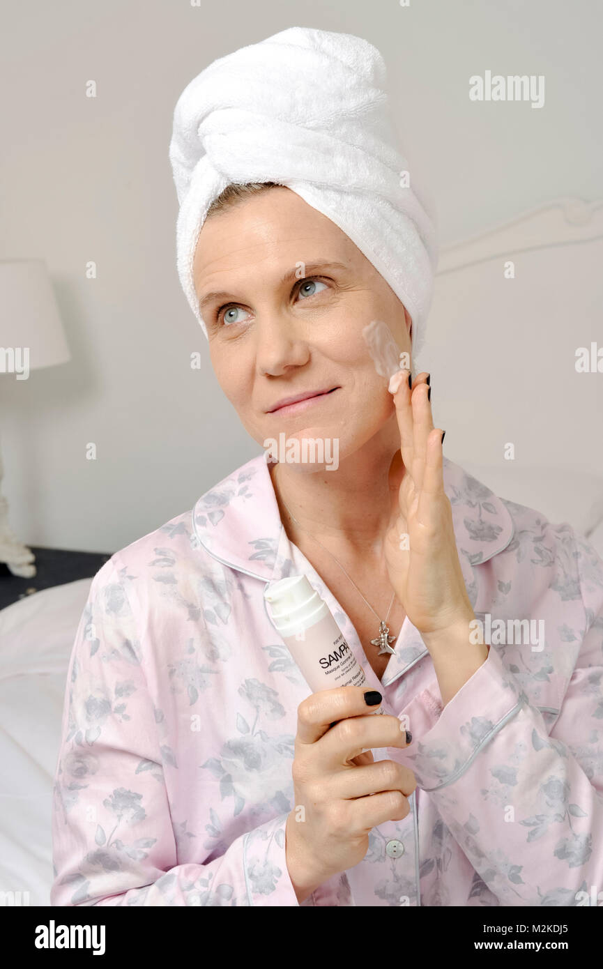Frau in ihrem Schlafzimmer mit Schönheitsbehandlungen, bevor sie schläft. Stockfoto