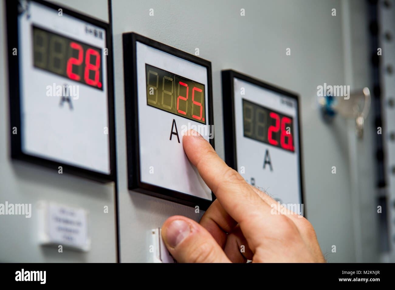 Mann hand auf Amperemeter close-up. Kontrolle der Energie System Parameter. Engineering Hintergrund. Stockfoto