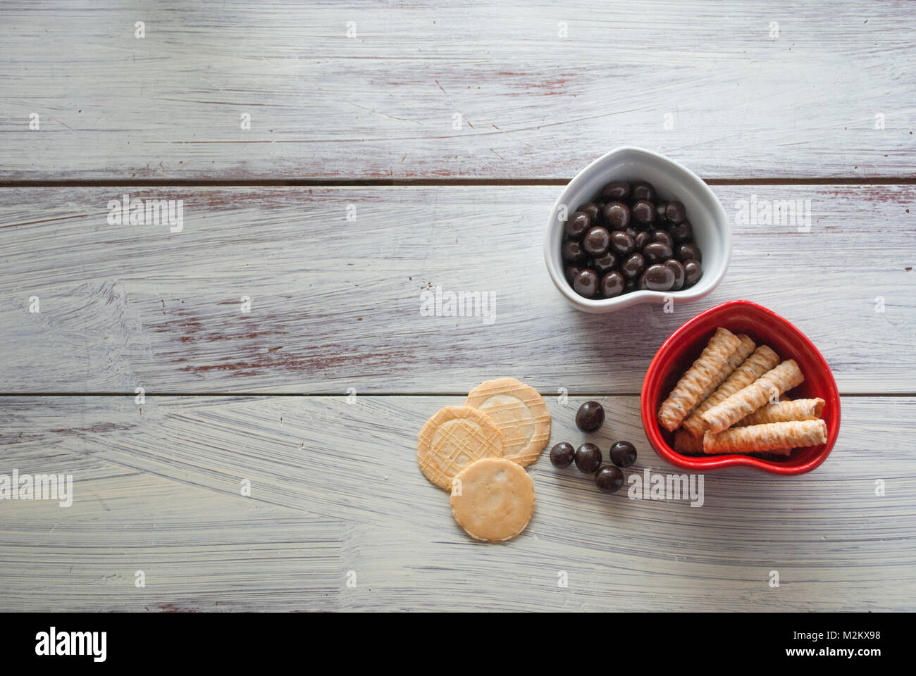 Zwei Herzen Form Schüsseln mit Plätzchen und Süßigkeiten auf vintage Holz- Oberfläche. Konzept der Feier Valentines Tag, Stück Liebe, gesunde Bio-Lebensmittel Stockfoto