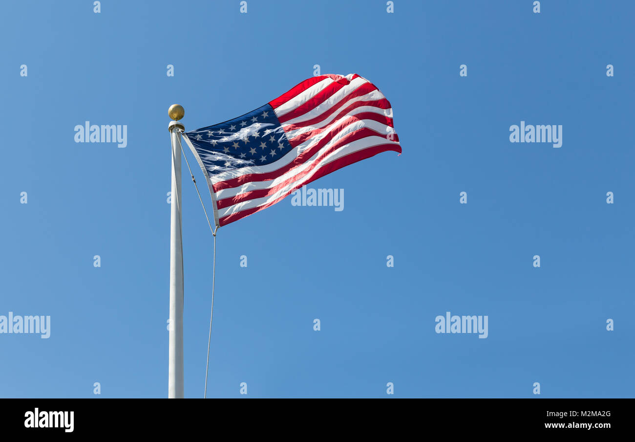 Die amerikanische Flagge auf dem Hintergrund des blauen Himmels, nach rechts gedreht Stockfoto