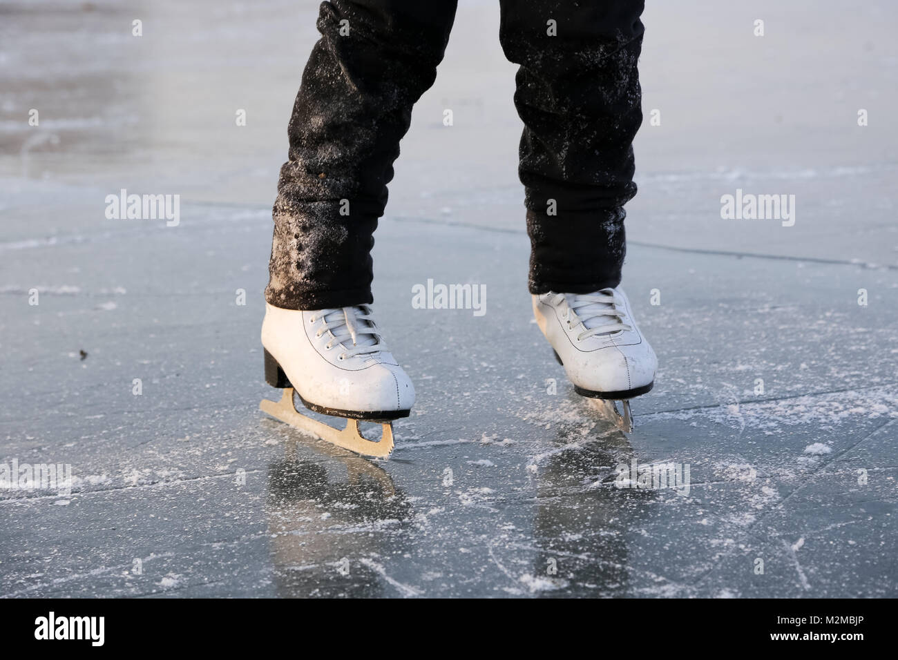 Junge Frau Eislaufen im Freien auf einem Teich an einem eiskalten Wintertag Stockfoto