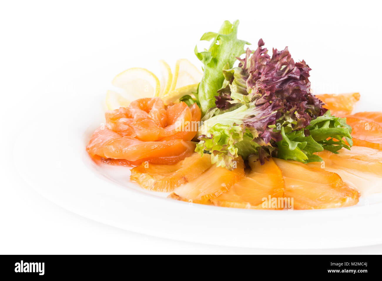 Sortierte Fische auf einem Teller mit Salat und Zitrone auf einem weißen Hintergrund. Eine Platte mit Fisch sortierten isoliert. Nach oben Schließen Stockfoto