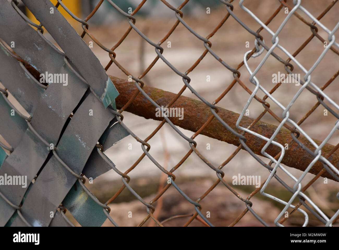 Rusty Maschendrahtzaun mit einer braunen und grauen städtischen Hintergrund verschwommen im Bokeh. Stockfoto
