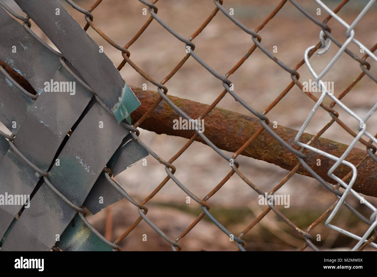 Rusty Maschendrahtzaun mit einer braunen und grauen städtischen Hintergrund verschwommen im Bokeh. Stockfoto