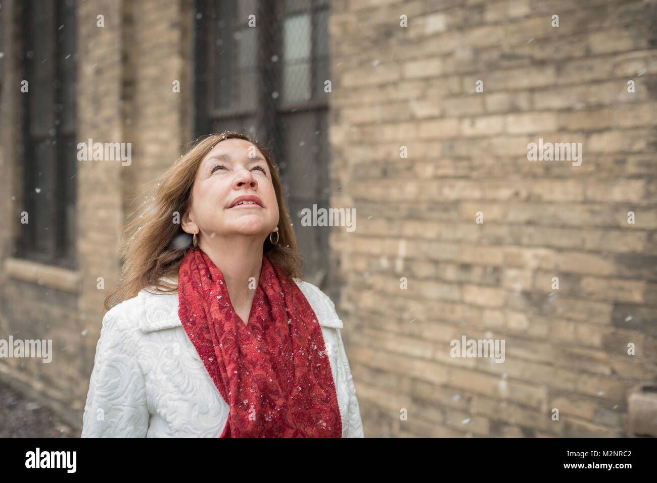 Urban Frau in Rot Schal zu Schneeflocken fallen und lächelnd Stockfoto