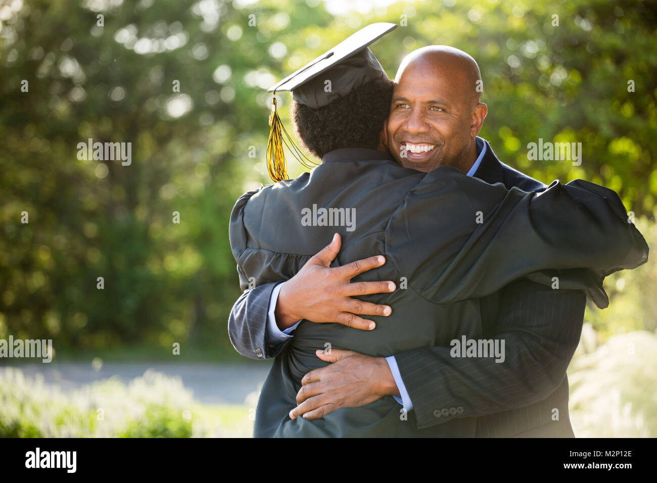 Vater umarmt seinen Sohn zu seinem Abschluss. Stockfoto