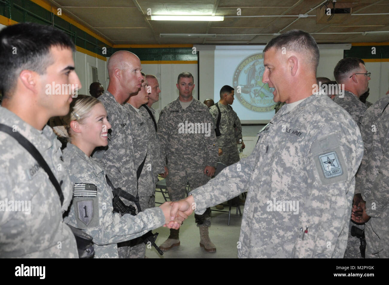 Sgt. Maj. der Armee Raymond F. Krämer III enthält eine Münze zu Spc. Melissa Stortz, Communications Specialist mit 2. Beraten und Unterstützen Brigade, 1 Infanterie Division, United States Abteilung - Zentrum und Mabel, Minn., Eingeborener, 24. Juni im Camp Liberty, Irak. Nach der Prägung Zeremonie, Chandler besprochen, viele der Probleme, mit denen die Soldaten heute in die Armee eingezogen wurde, einschließlich der jüngsten Änderungen der Uniformen und mögliche Änderungen an der körperlichen Fitness Bewertungen und Verweilzeit nach Bereitstellungen. (U.S. Armee Foto: Staff Sgt. Justin Phemister, 2. AAB, 1. Inf. Div., USD-C) Kommunikation sp Stockfoto