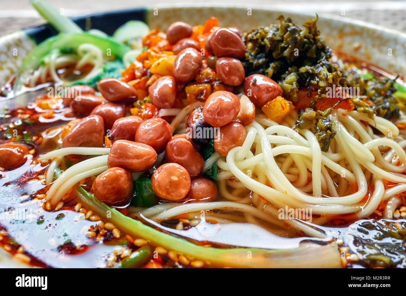 Würzige Nudelsuppe mit Gemüse, Kräutern, Erdnüssen und Koriander, beliebt in der Provinz Yunnan, geringe Tiefenschärfe, China. Stockfoto
