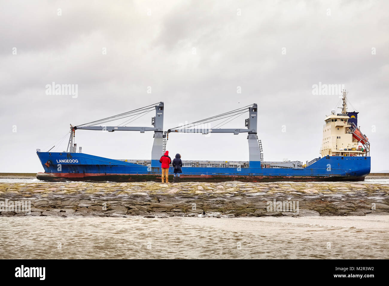 Swinoujscie, Polen - Januar 28, 2018: die Menschen Langeoog cargo Schiff verlässt den Hafen von Swinoujscie an einem bewölkten Tag im Winter beobachten. Stockfoto