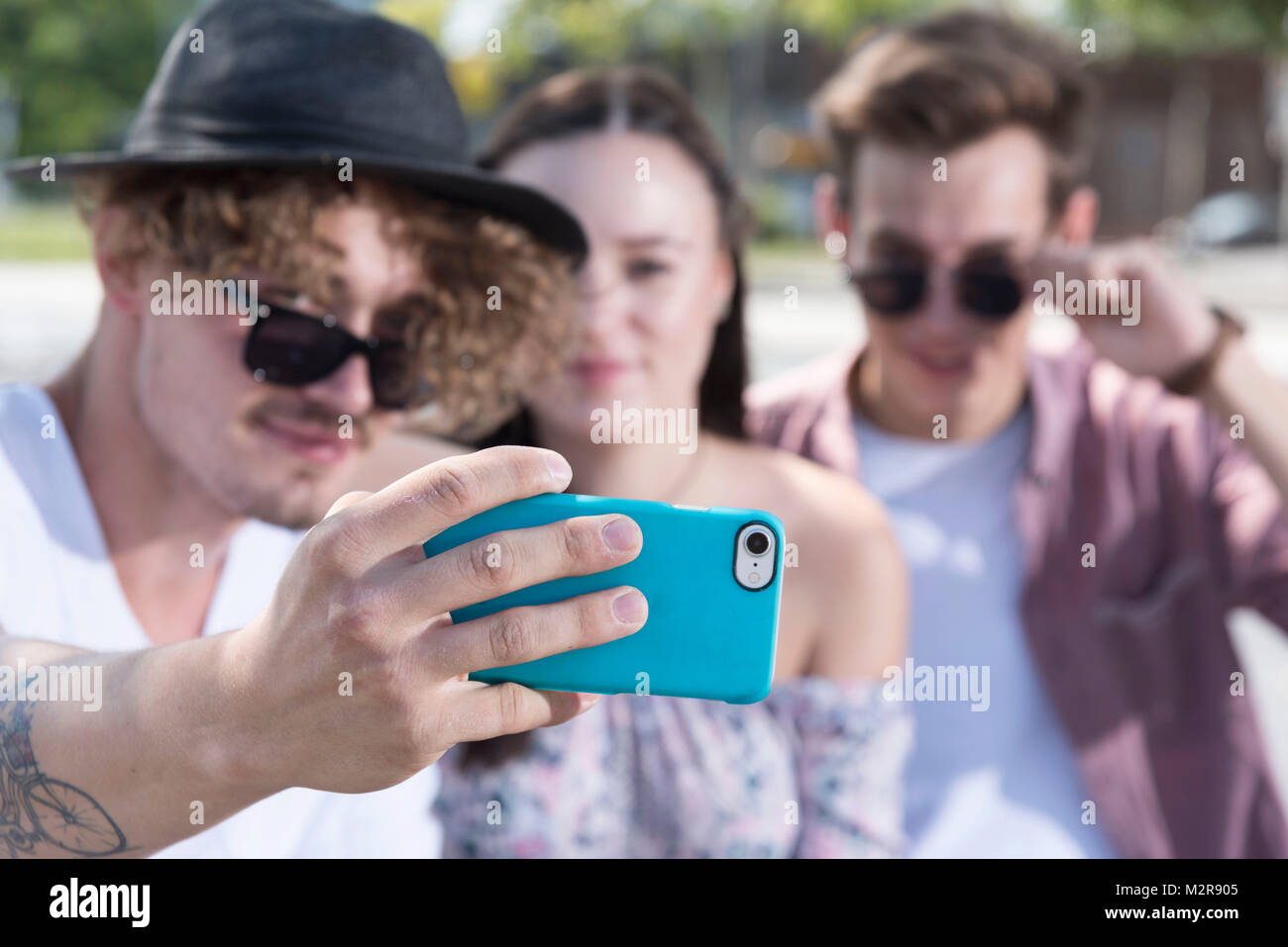 Zwei junge Männer und ein Mädchen außerhalb in der Nähe Smartphone Stockfoto