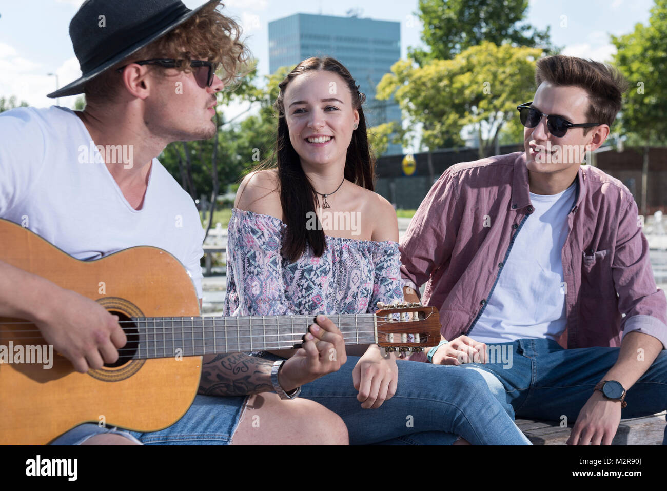 Zwei junge Männer und ein Mädchen außerhalb der Gitarre Stockfoto