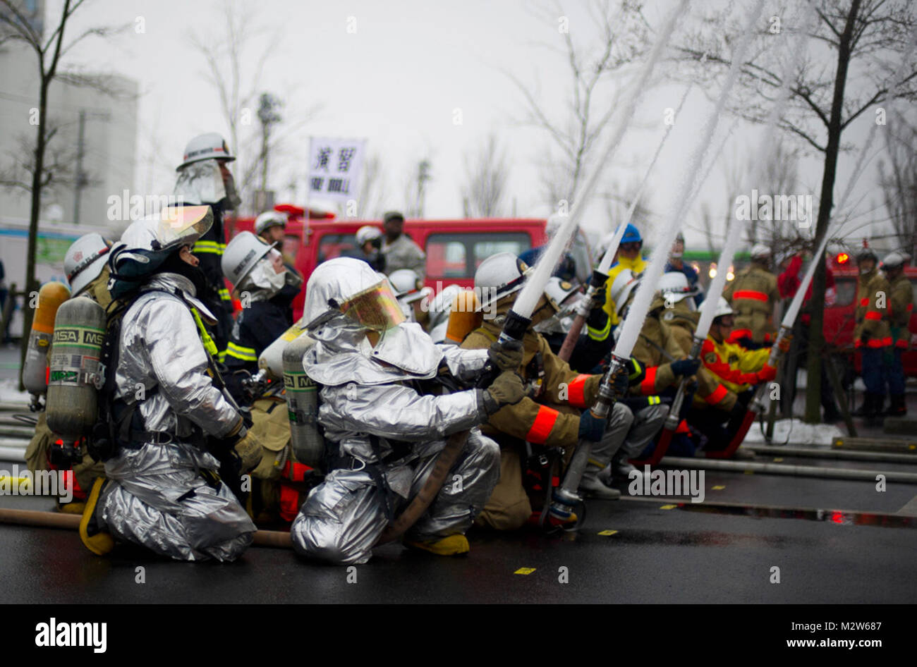 YOKOTA AIR BASE, Japan - Japanische Feuerwehrmänner von Fussa, Hamura, Mizuho und Yokota Air Base, simulieren Löschmittel ein brennendes Gebäude während der Fussa Feuerwehr Rettung Antwort Übung außerhalb eines japanischen Kaufhaus, 2. März 2012. Mehr als 130 Feuerwehrleute im Falle teilgenommen. (U.S. Air Force Foto/Staff Sgt. Tschad C. Strohmeyer) Fussa Feuerwehr Rettung Antwort Übung von # FIRMA PACOM Stockfoto