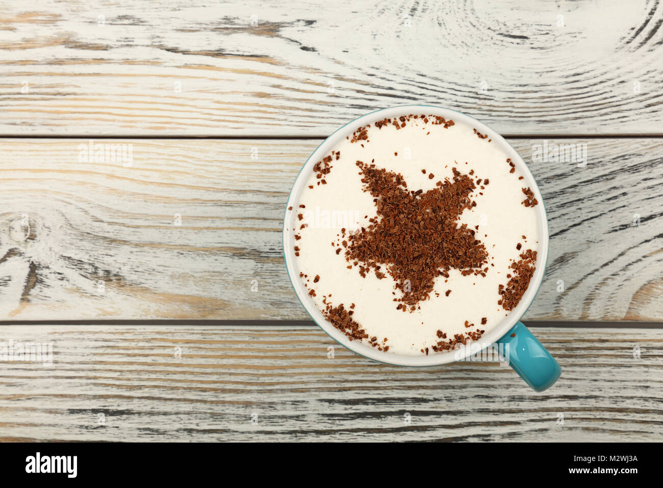Close up Blue Cup voller Latte Cappuccino mit sternförmigen Schokolade auf Milchschaum über Hintergrund der weißen vintage Holzbohlen Tabelle, in der Nähe Stockfoto