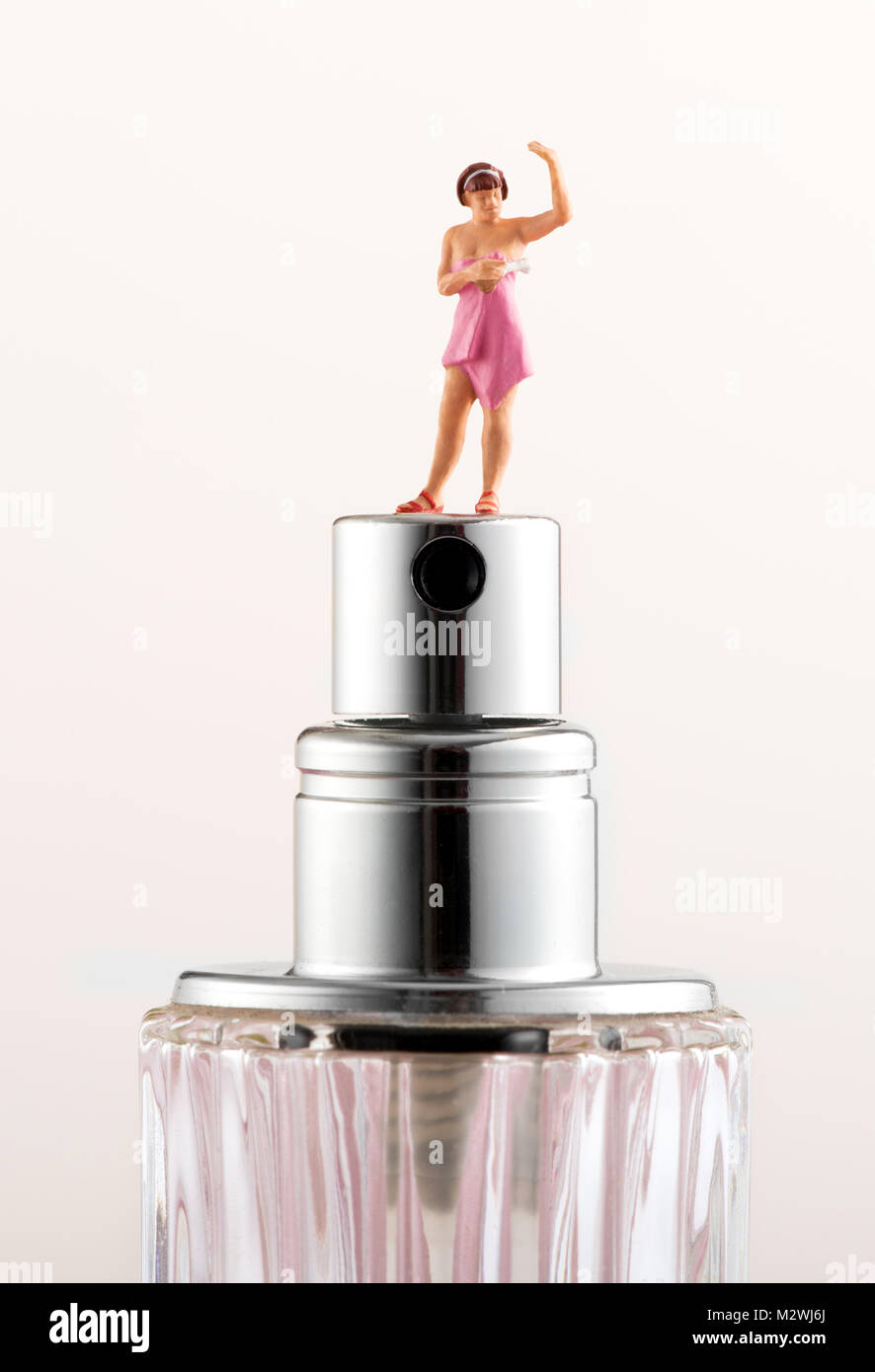 Miniatur Frau mit einem Handtuch auf dem Zerstäuber eines Duft Flasche in ein Konzept der persönlichen Hygiene und Gesundheit gewickelt um Ihren Stockfoto