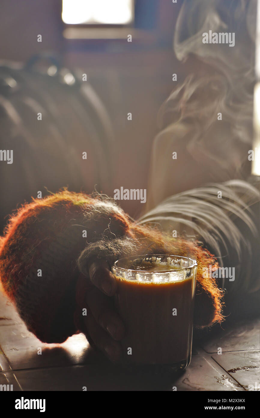 Man Getränke ein heisses Glas Tee oder Kaffee in der Hütte zu warm Stockfoto