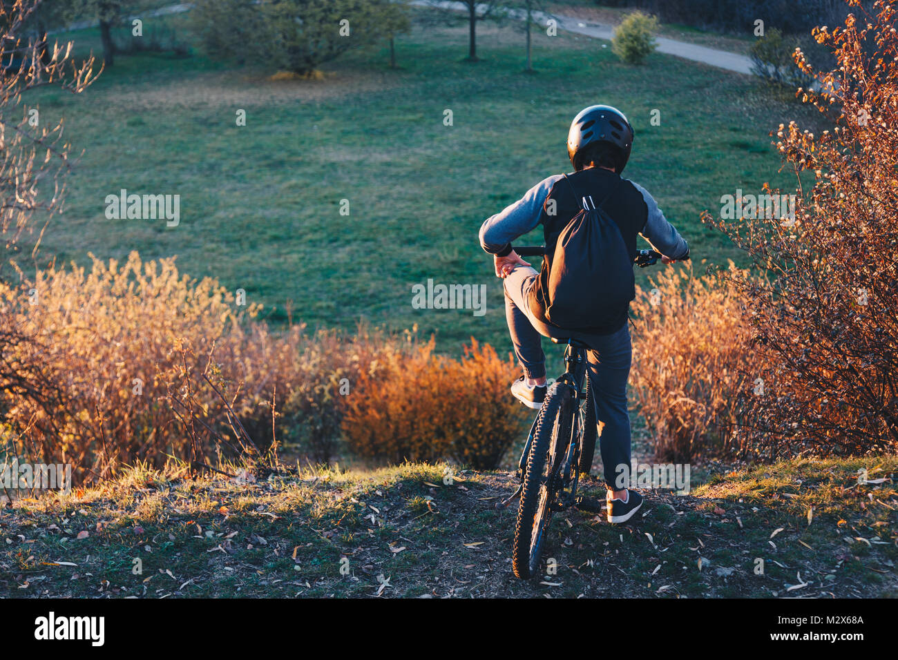 Mountainbiker steht am Rande eines Hügels bei Sonnenuntergang vor dem Reiten Downhill - Erfolg und gewinnende Konzept. Stockfoto