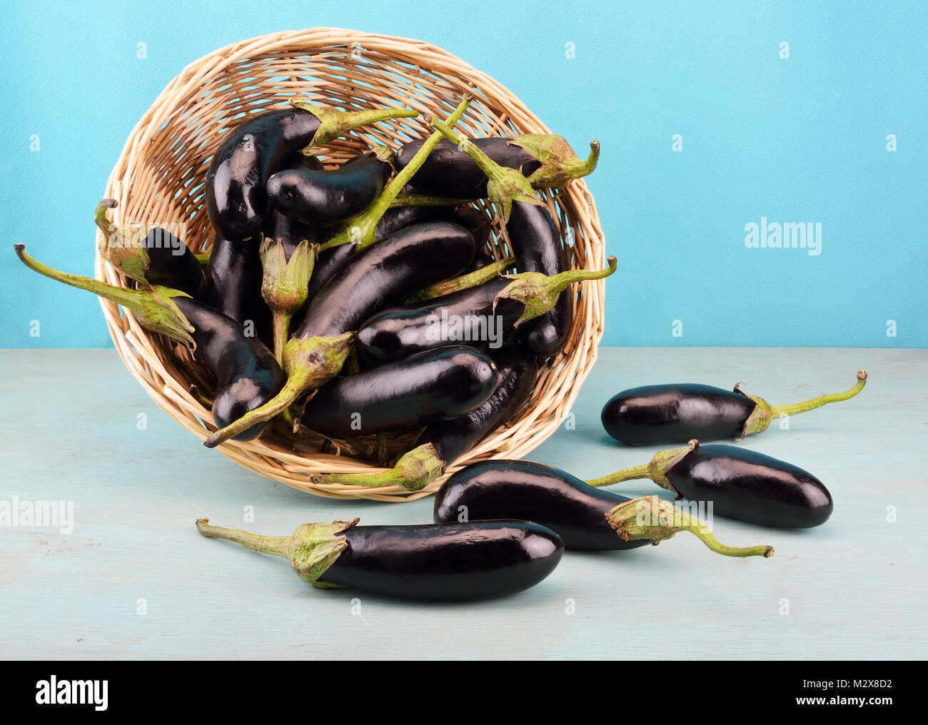 Baby Auberginen in einem Korb auf einem hölzernen blauen Tabelle Stockfoto