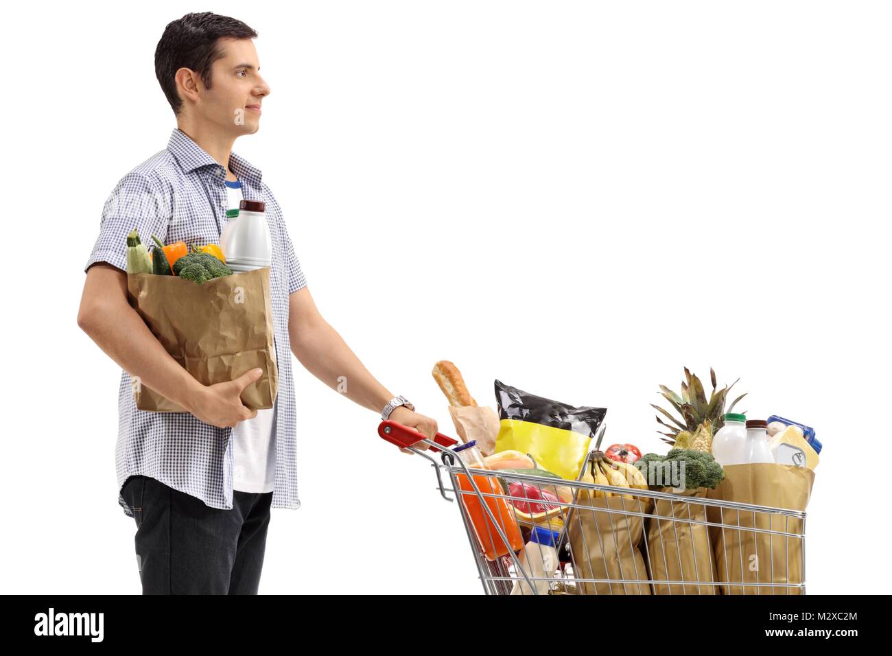 Junger Mann mit einer Einkaufstasche und einen Warenkorb mit Lebensmitteln auf weißem Hintergrund gefüllt Stockfoto